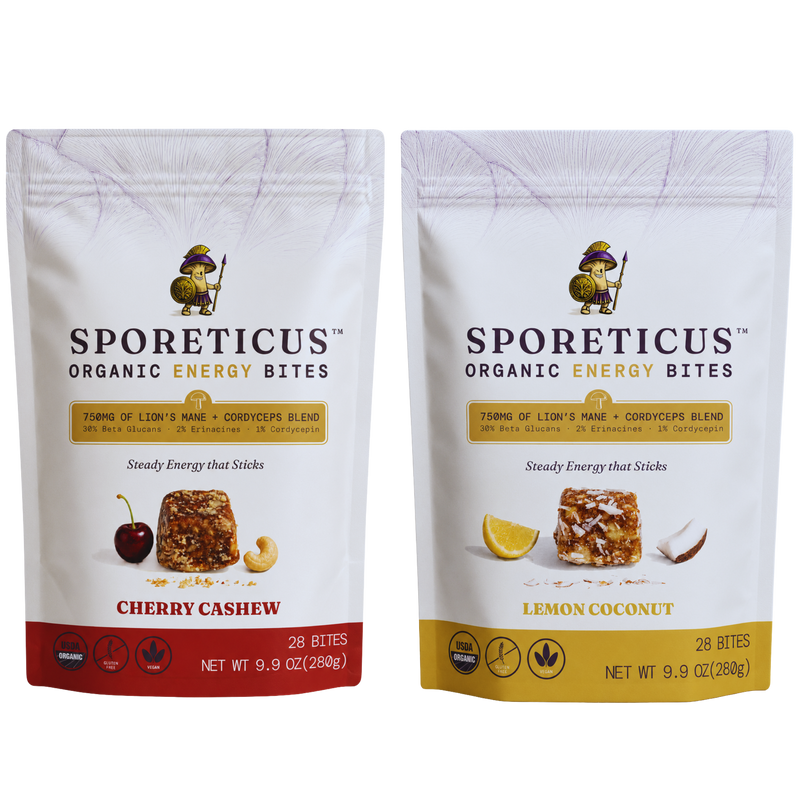 Two stand-up pouches of Sporeticus Organic Energy Bites on a white background. The left pouch is Cherry Cashew with a red bottom band and cherry/cashew imagery.